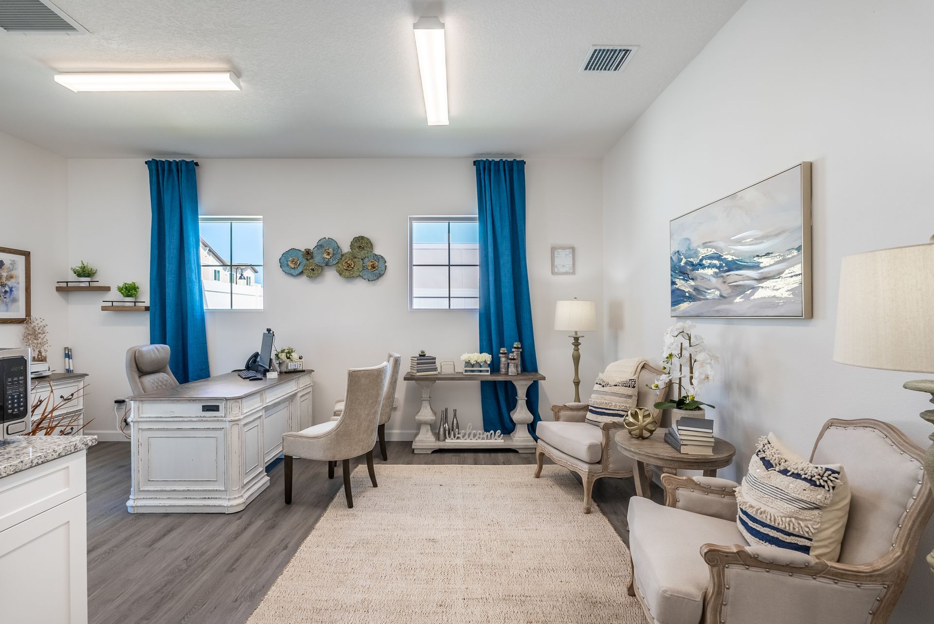 a living room with a desk , chairs , and a rug .