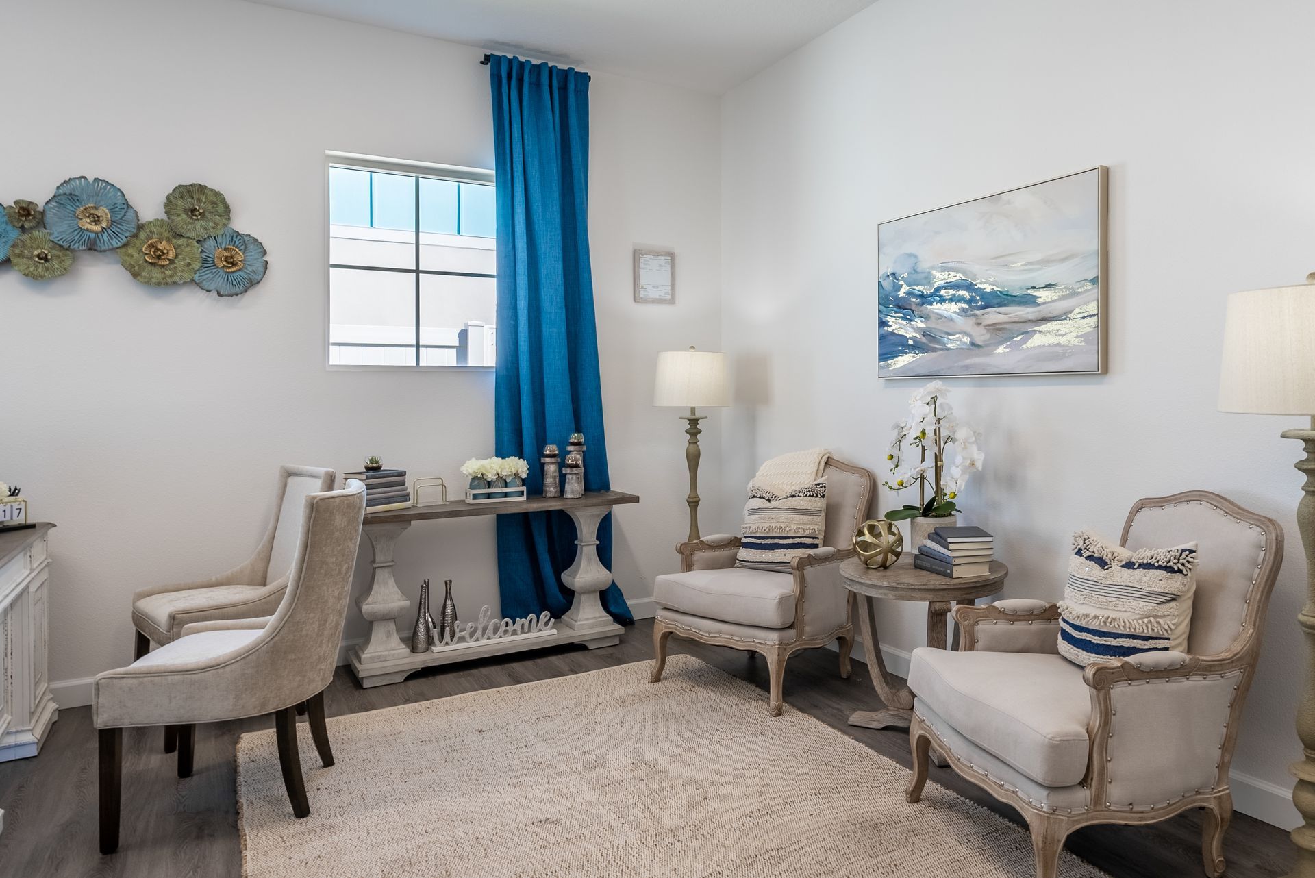 a living room with two chairs , a table and a painting on the wall .