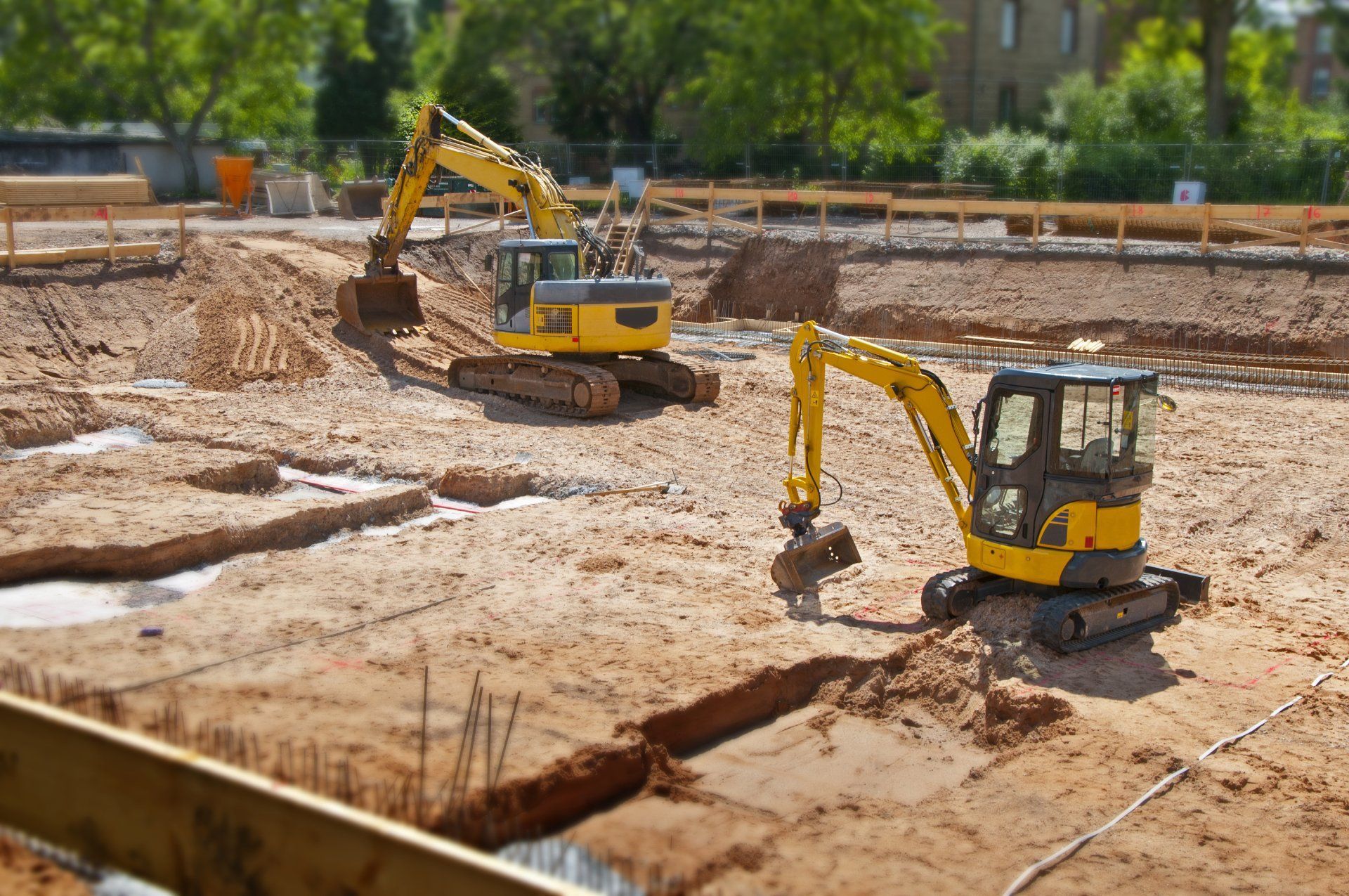Two yellow excavators are working on a construction site.