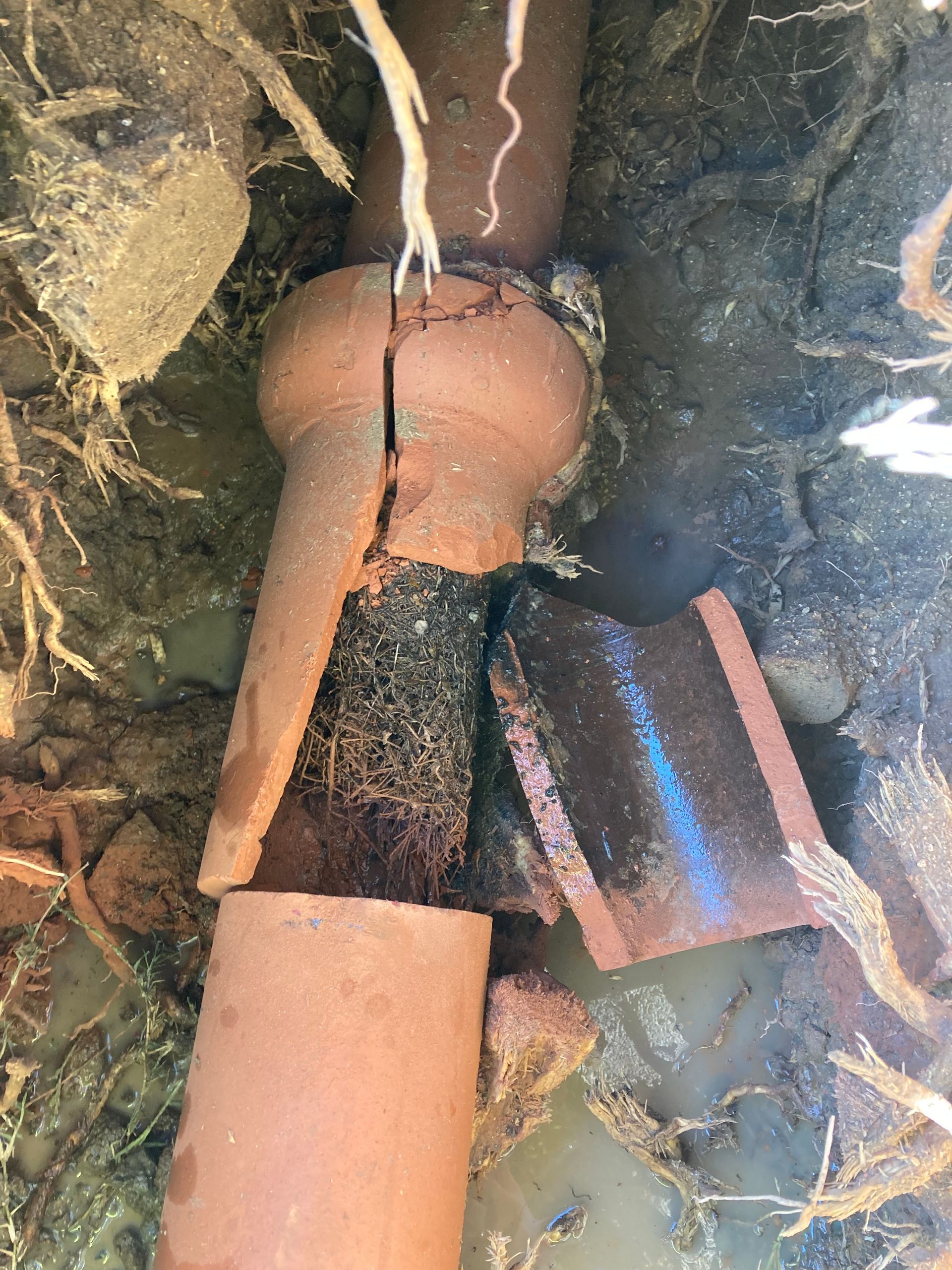 A close up of a broken pipe in the ground.