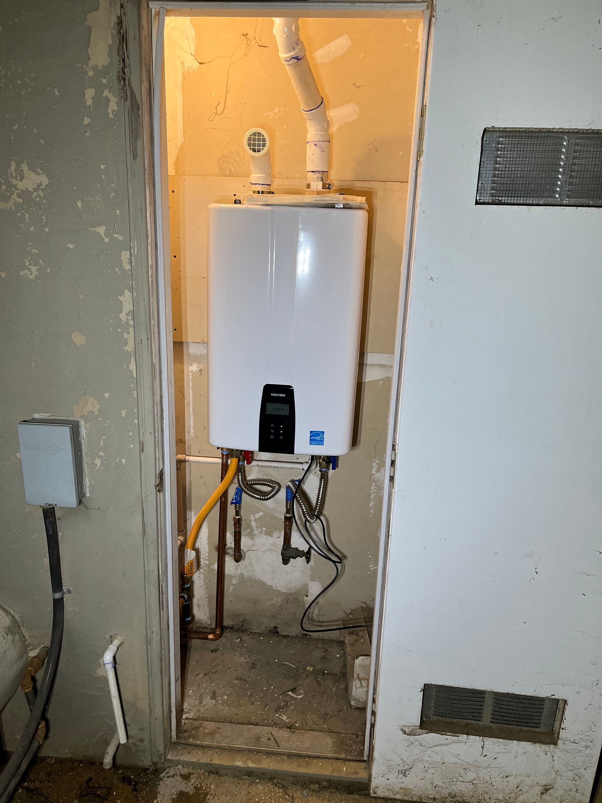 A water heater is installed in a room next to a door.