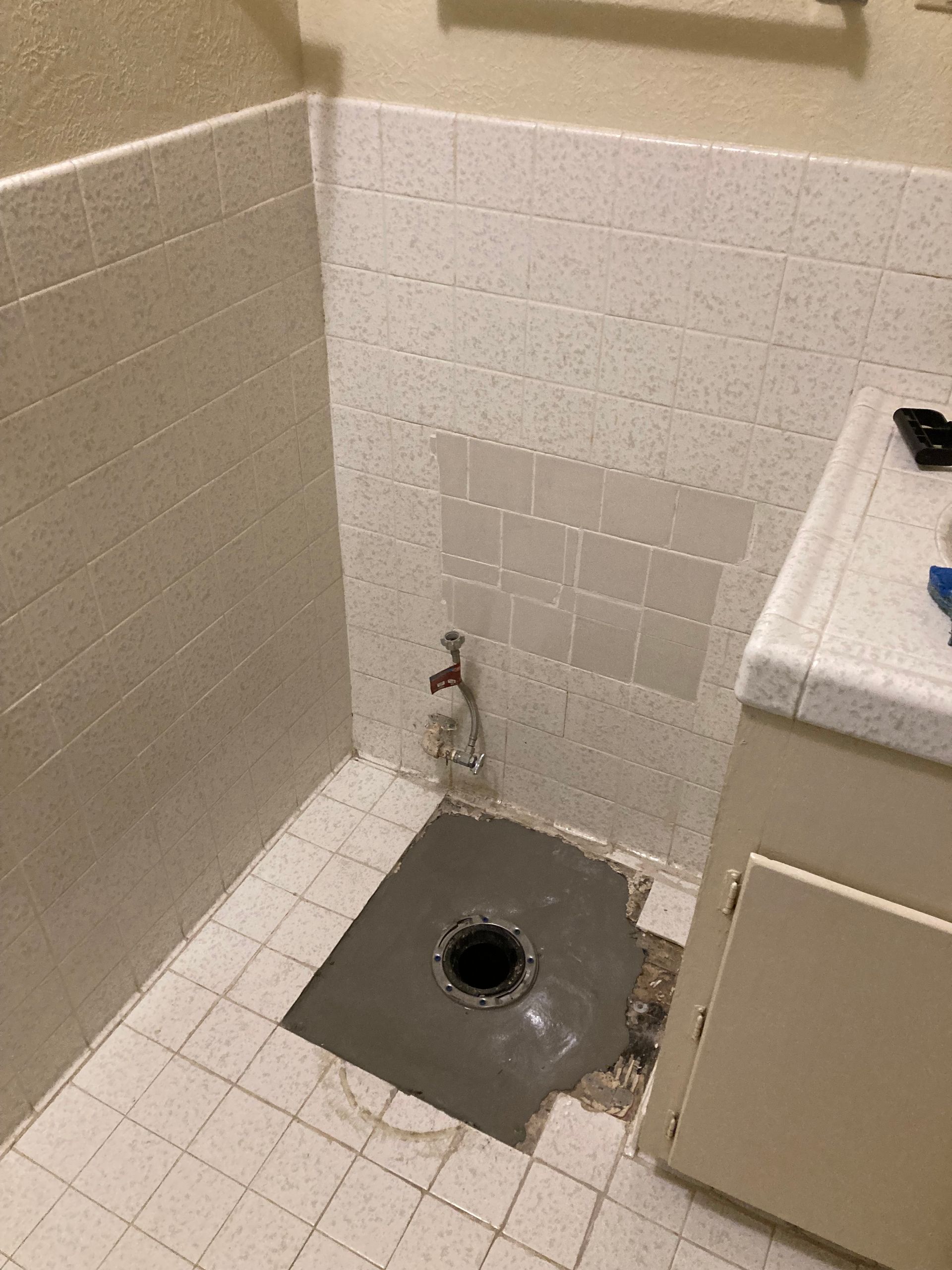 A bathroom with a hole in the floor and a sink.
