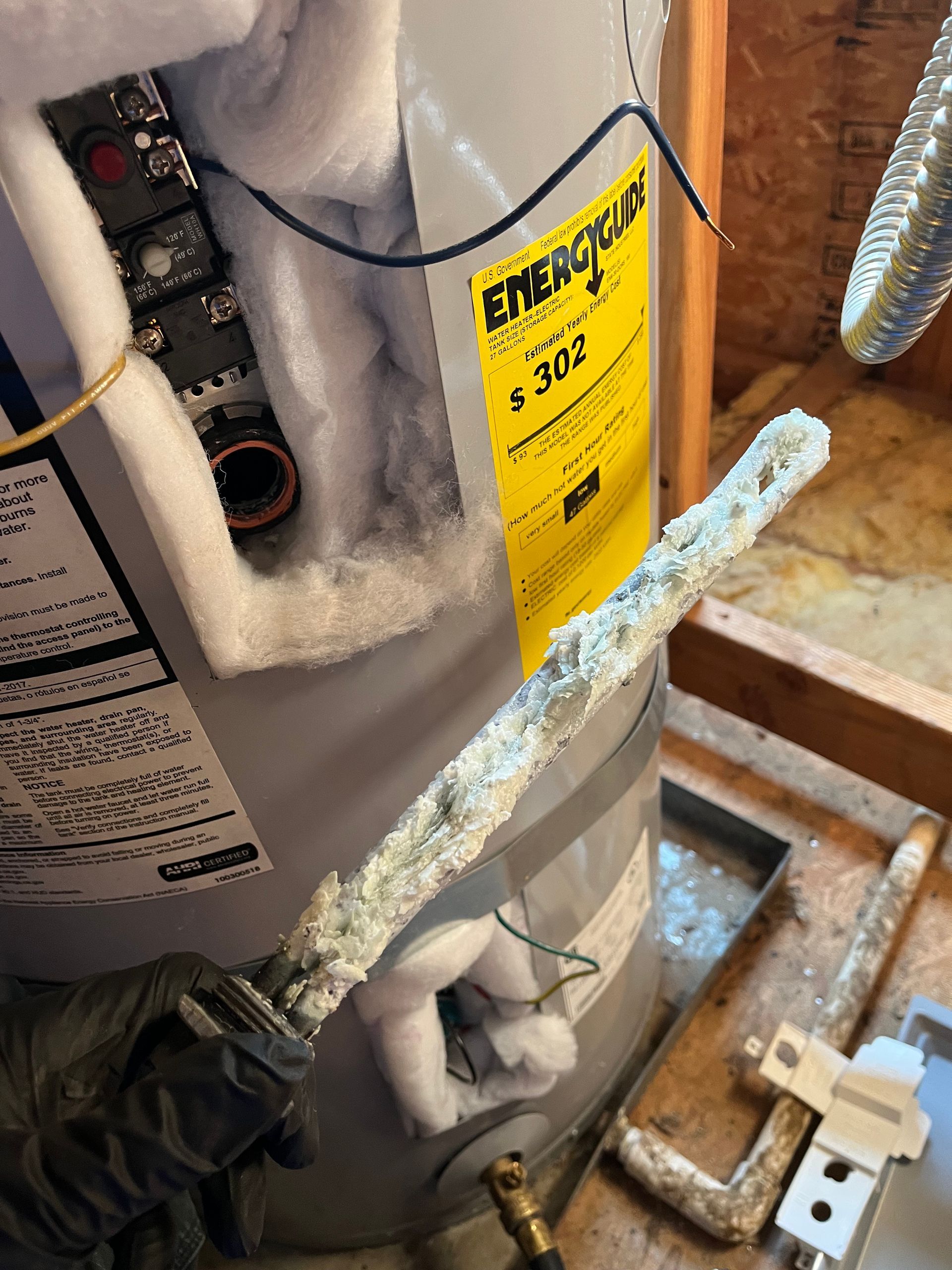 A water heater with a yellow energy star label on it is sitting on a wooden table.