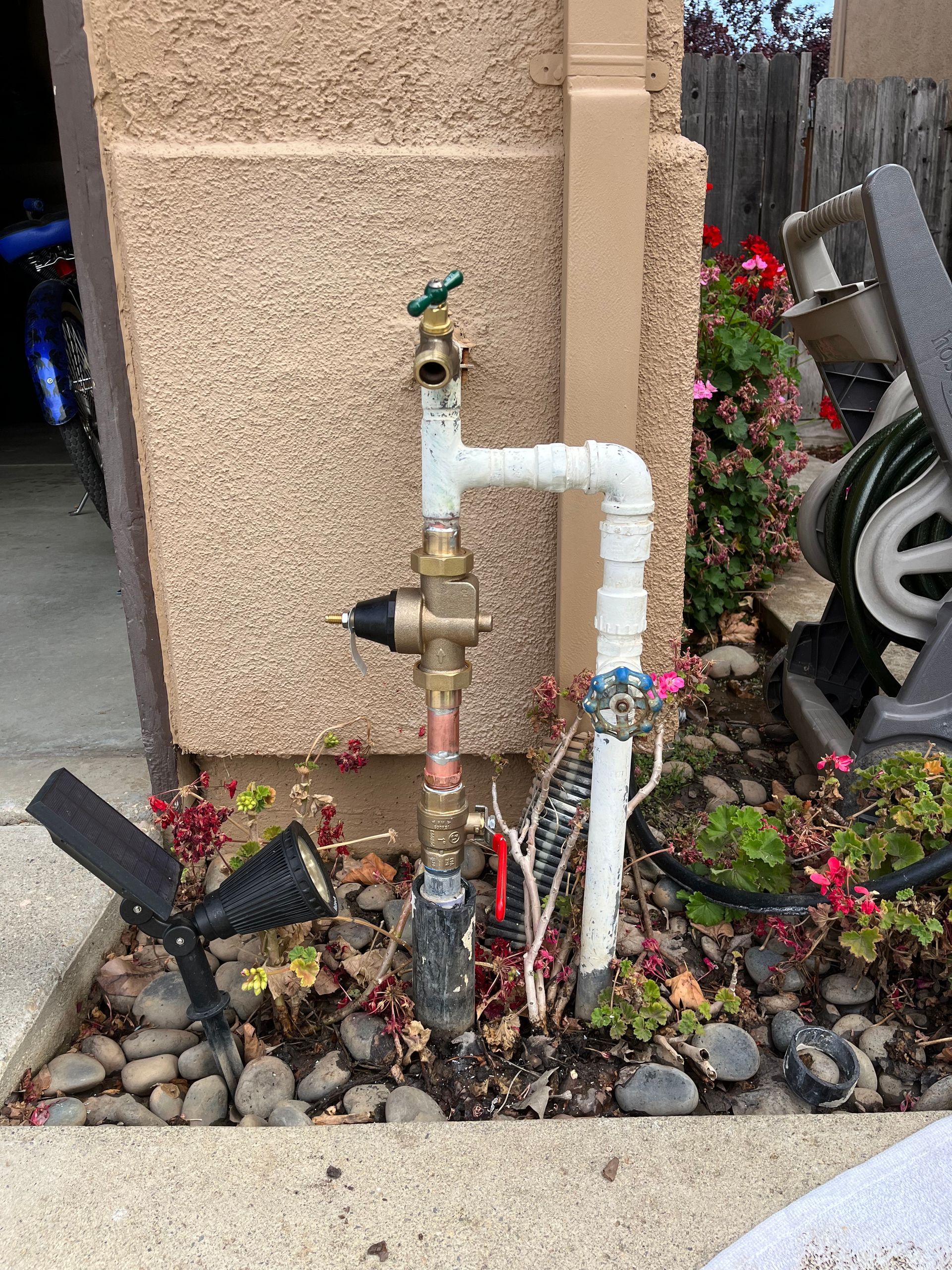 A hose is attached to a faucet on the side of a building.