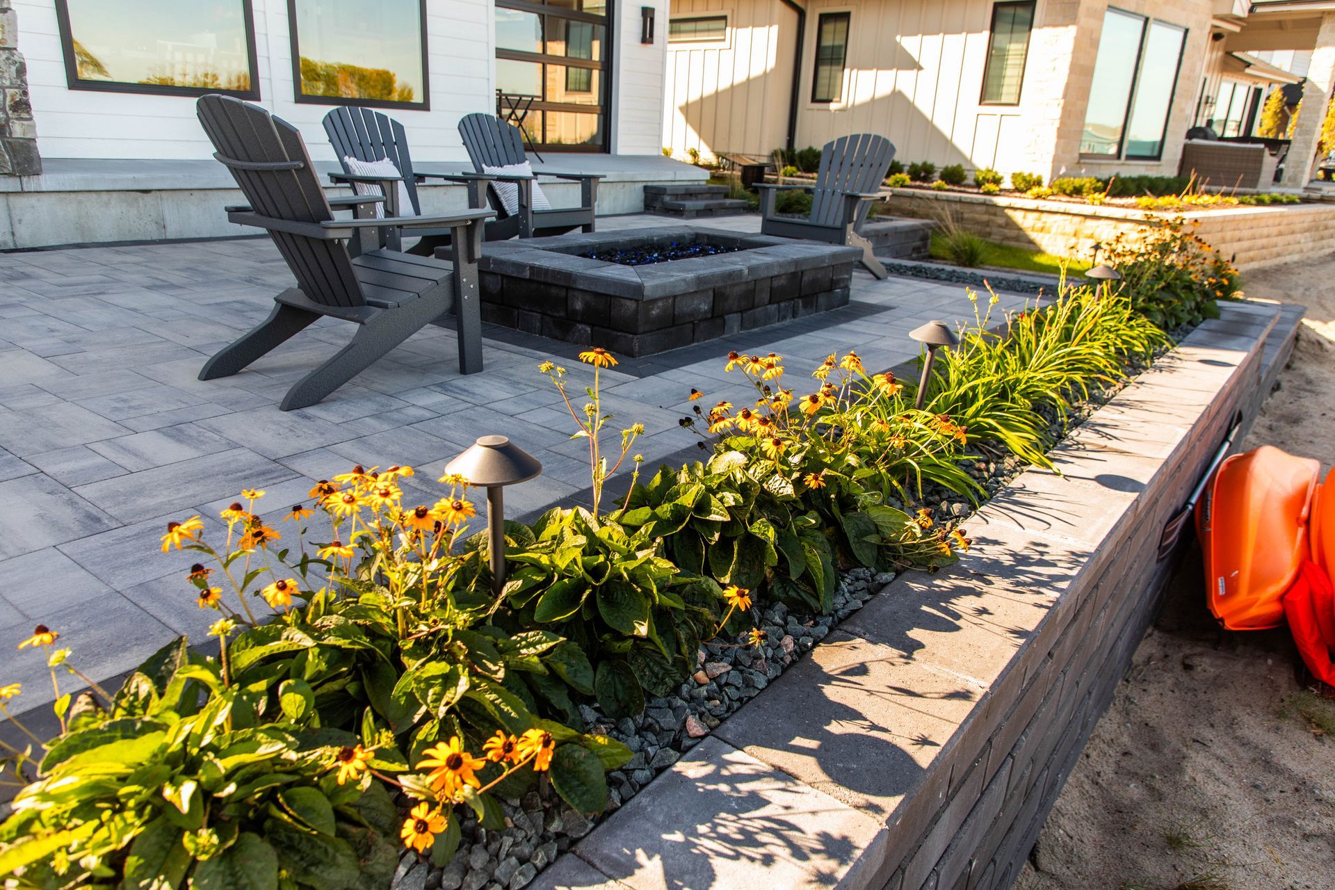 A patio with a fire pit and chairs in front of a house.