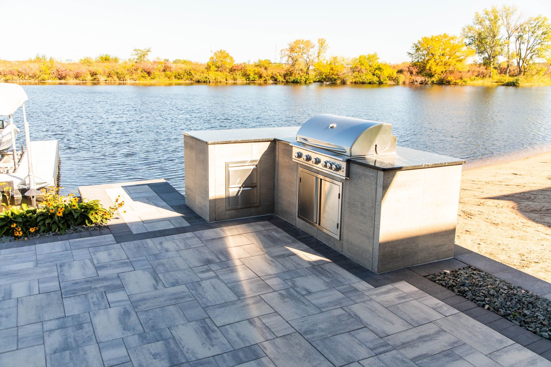 A grill is sitting on a patio next to a lake.