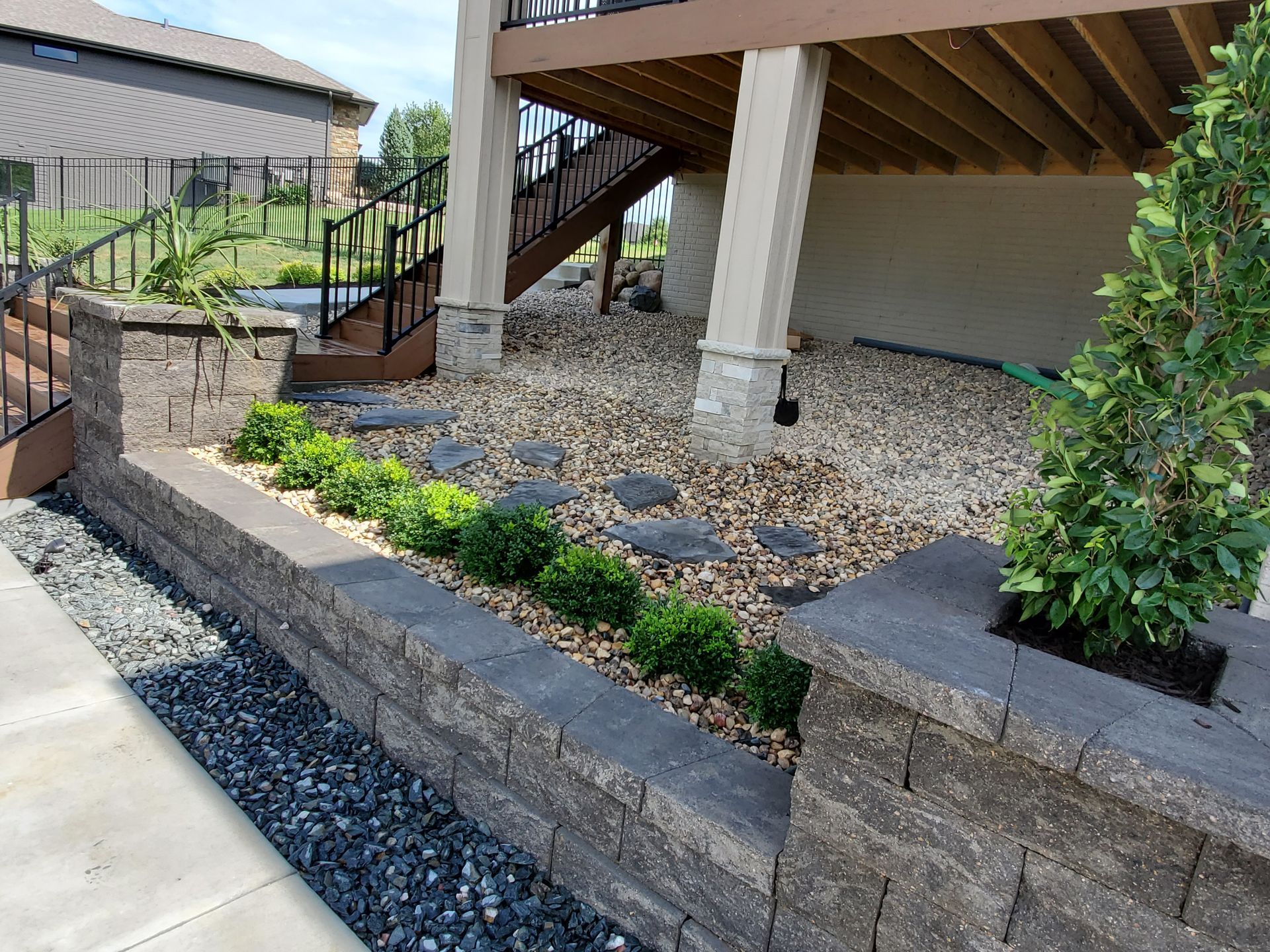 A brick wall with plants and rocks in front of a house
