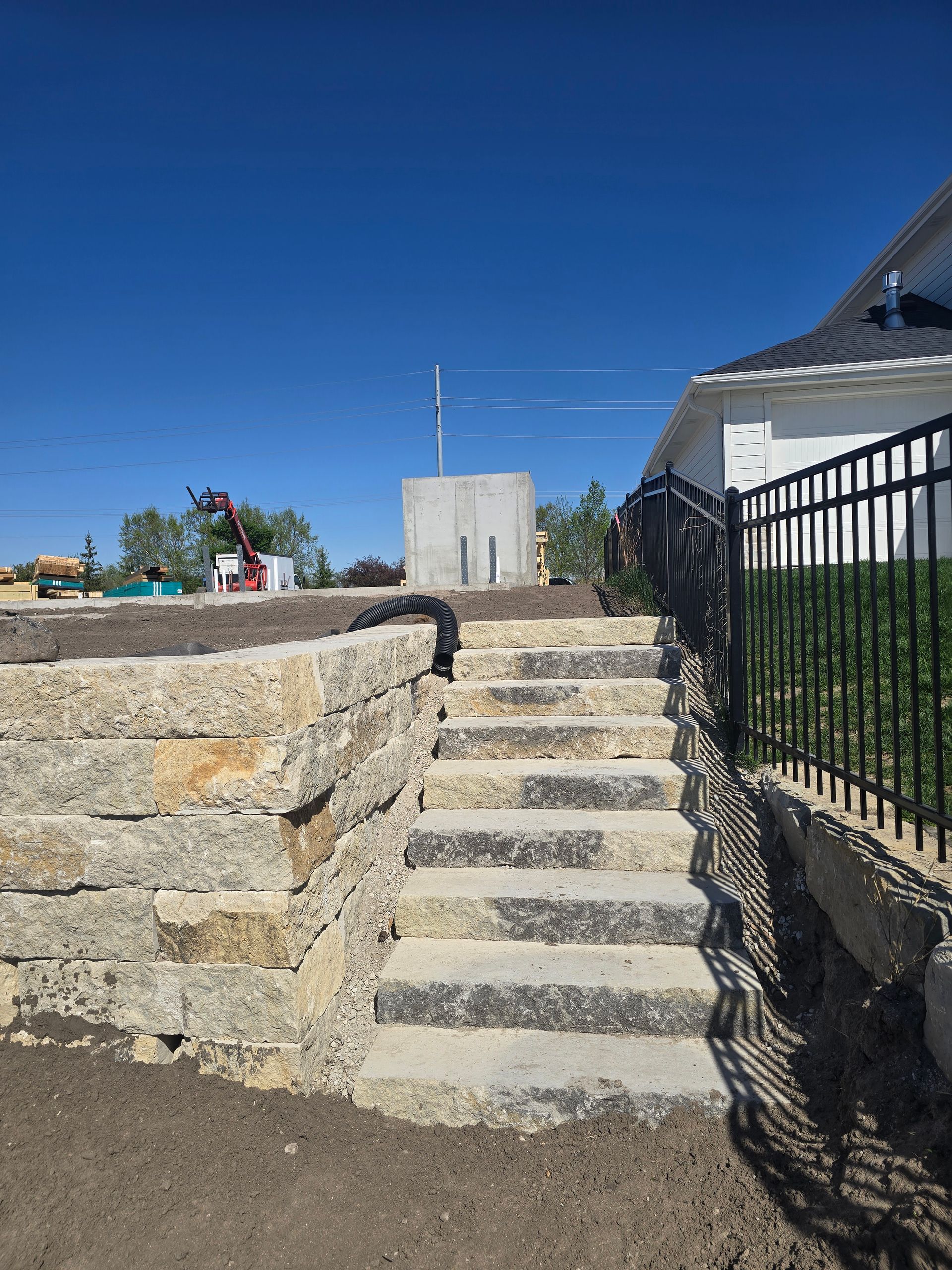 A set of stairs leading up to a house next to a stone wall.