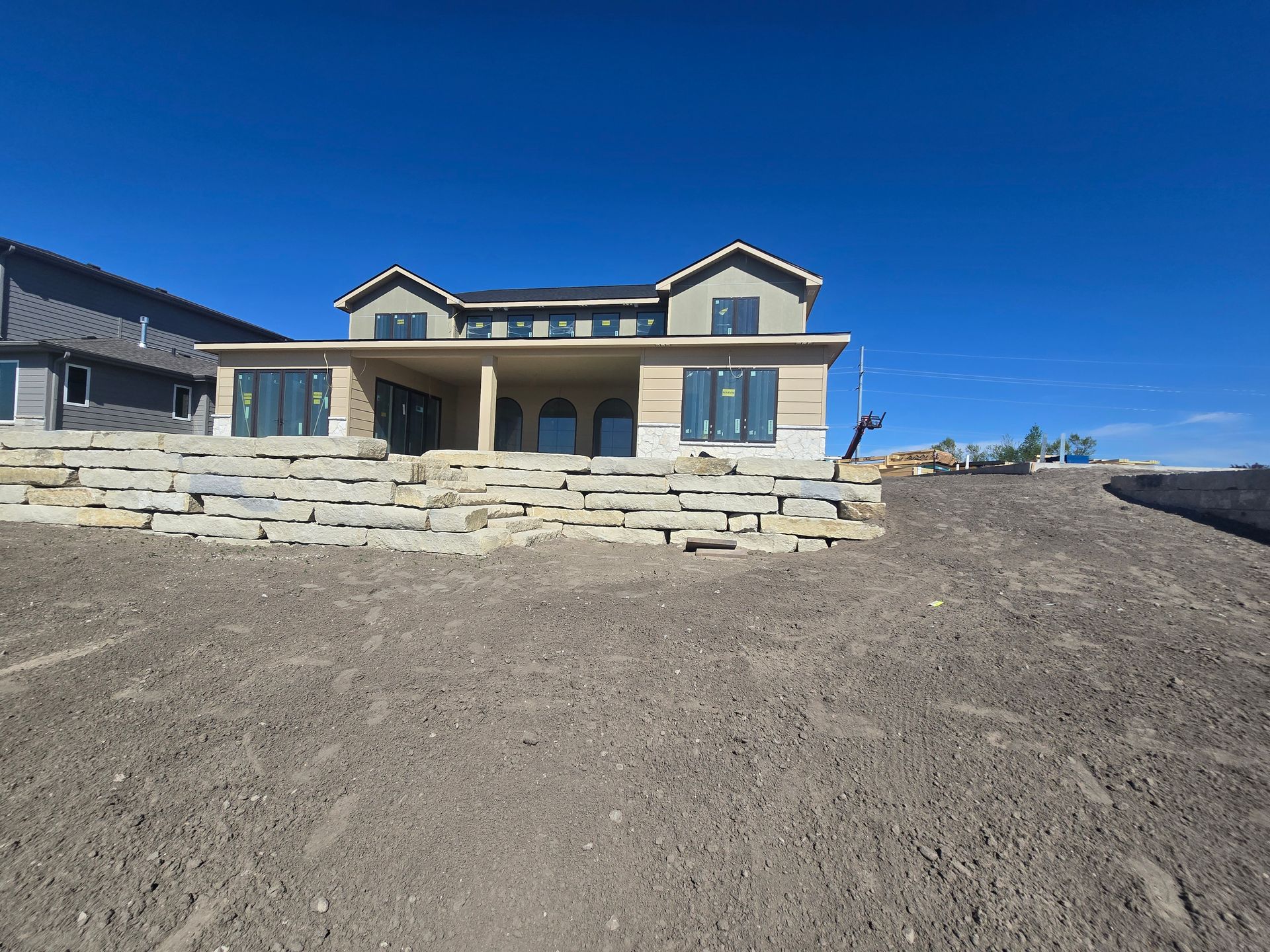 A large house is sitting on top of a dirt hill.