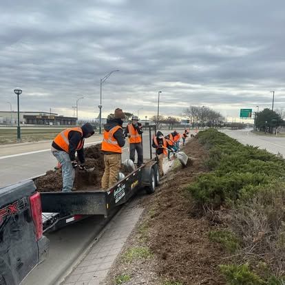 A group of people are working on a sidewalk next to a road.