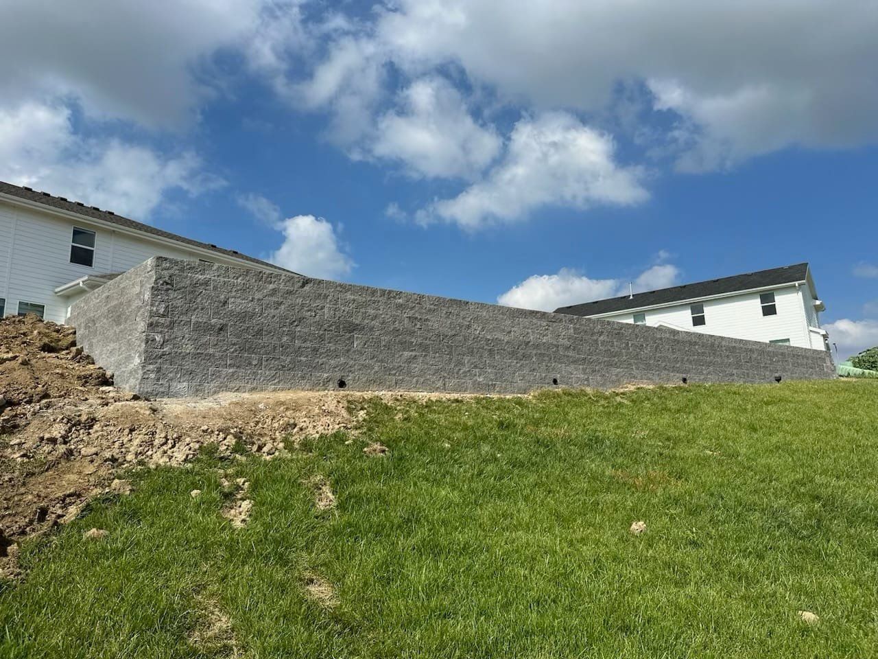 A large stone wall is being built in the backyard of a house.