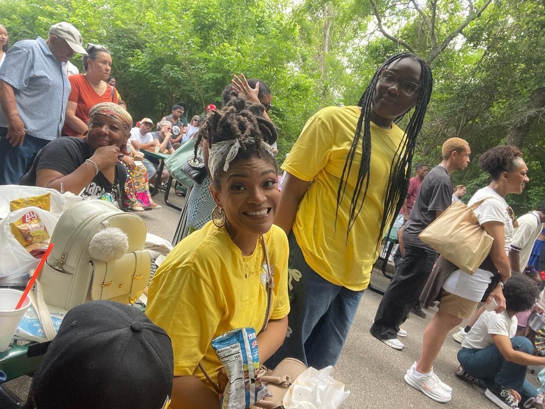 Children in yellow shirts smiling at an outdoor park event with a crowd in the background