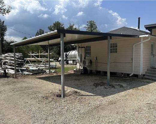 Carport attached to a white building; metal frame, gravel ground.