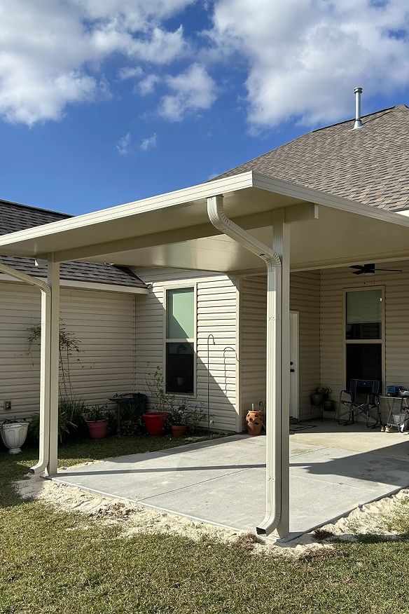 Beige-colored patio cover attached to a house with a concrete patio and a grassy yard.