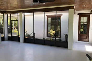 Sunroom with glass walls, door, and planters against a white stucco exterior.
