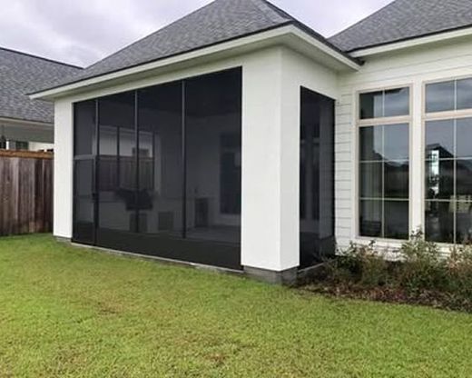 Screened-in porch attached to a white house with dark gray screen, black trim, and green grass.