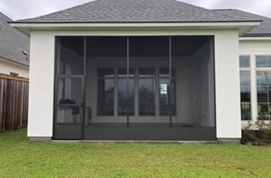 Enclosed screened porch with dark screens, white walls, and gray roof, attached to a house.