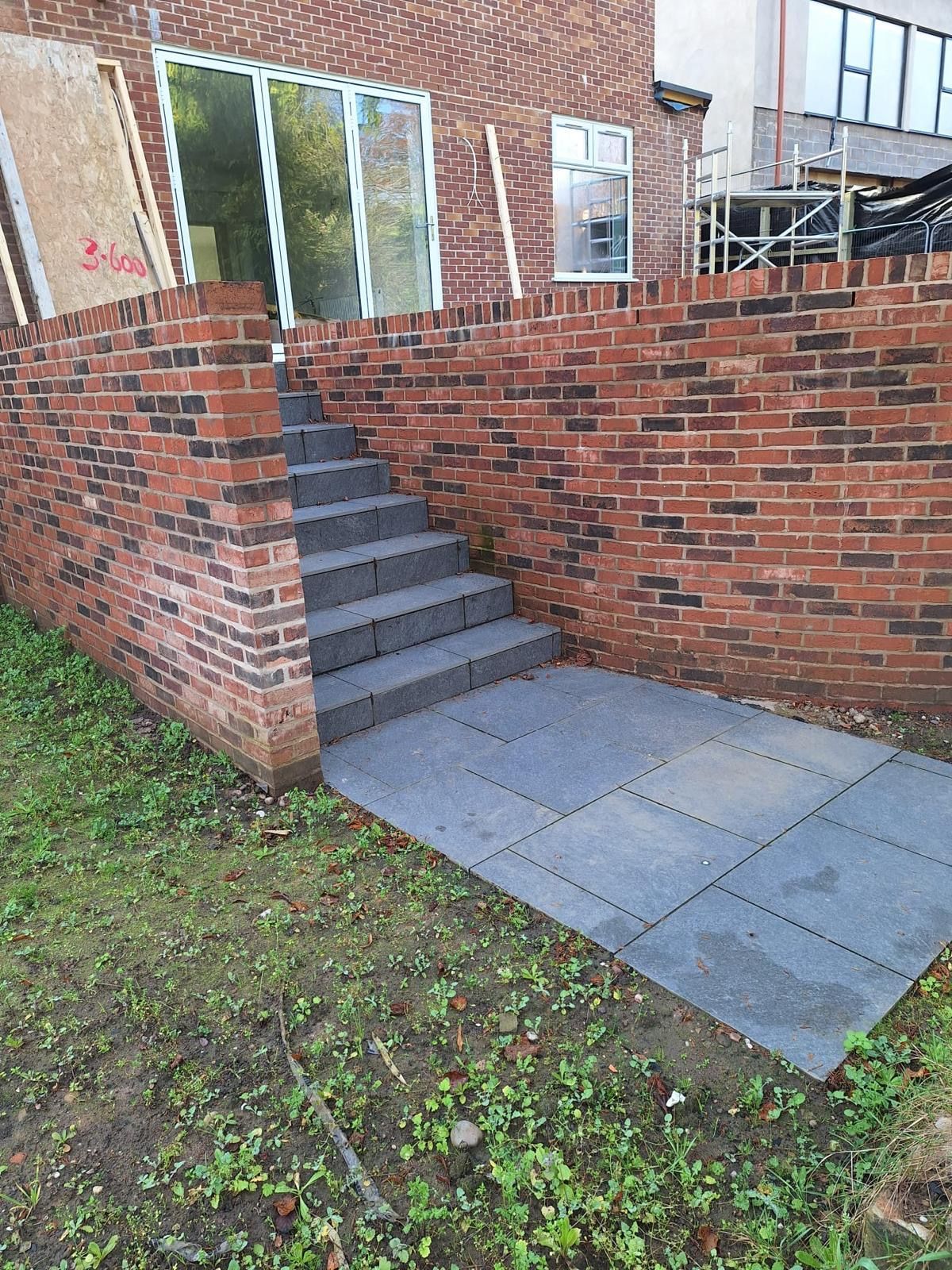 Brick entrance with steps and a concrete ramp beside a grassy yard.