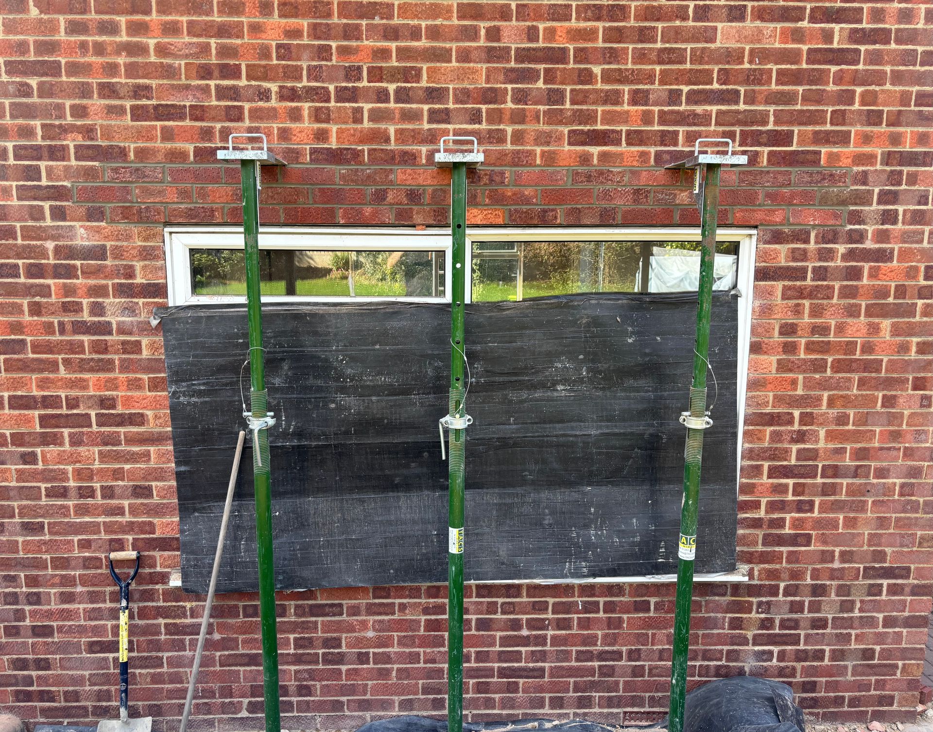 Two green-backed benches against a brick wall, with two black panels attached in front.