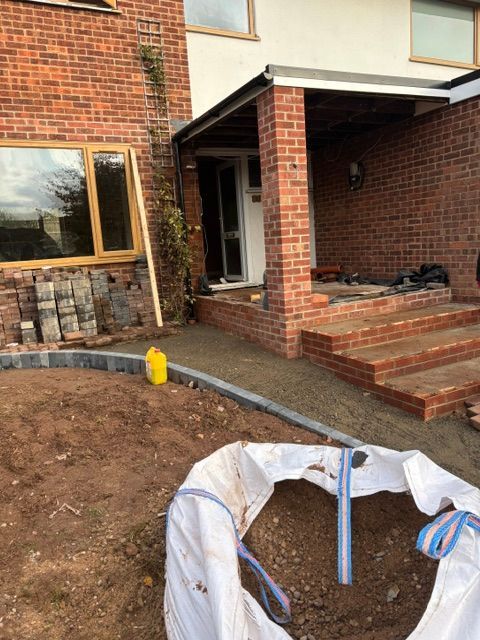 Brick house entrance with steps, front yard dirt, and a covered circular opening in the foreground
