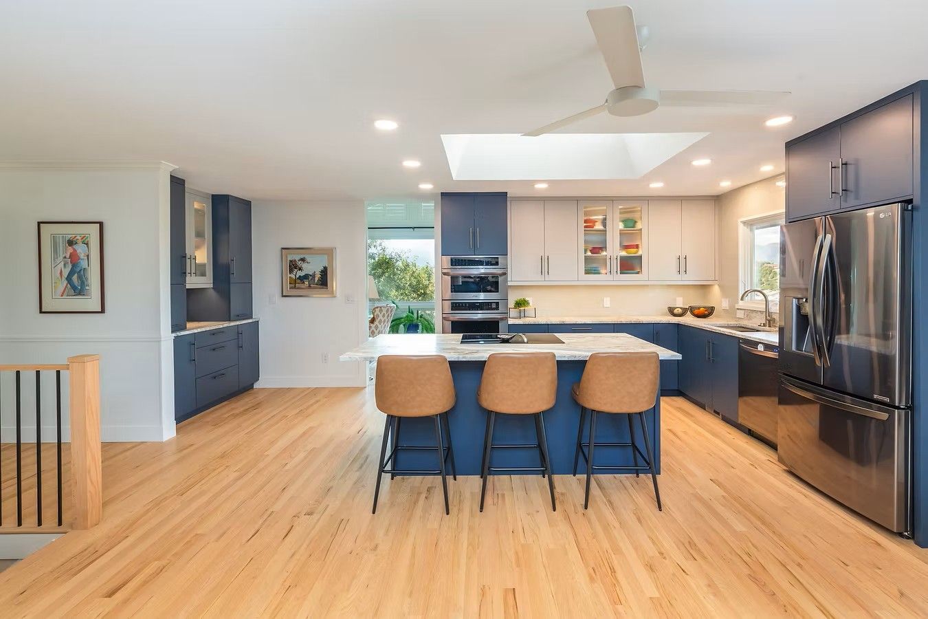 Modern kitchen with blue cabinetry, light wood floors, and island with stools.