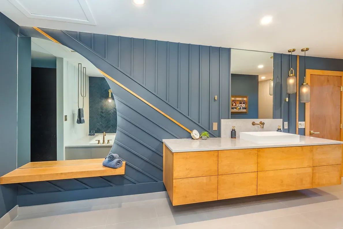 Modern bathroom with blue paneling, wood vanity, and gold accents.
