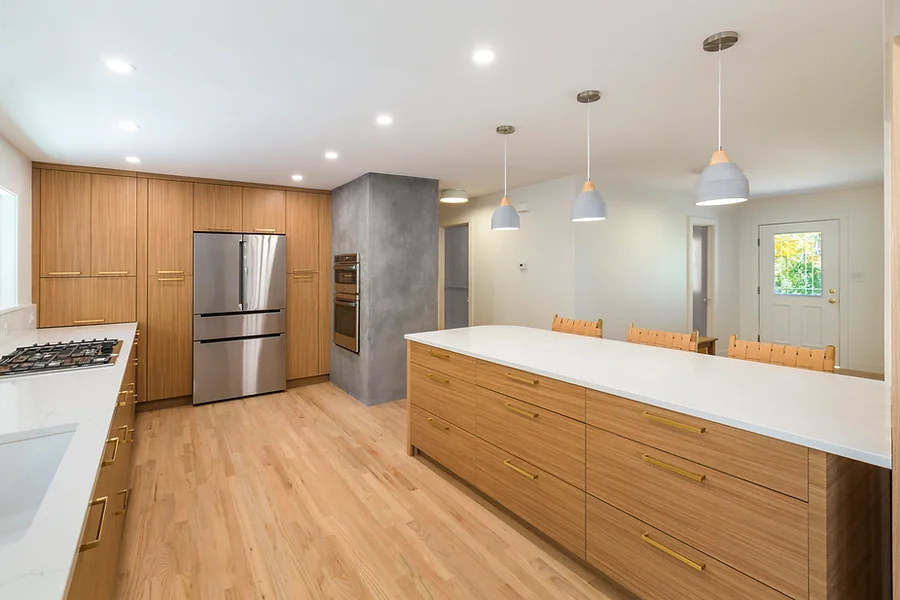 Modern kitchen with light wood cabinets, stainless steel appliances, and a large island.