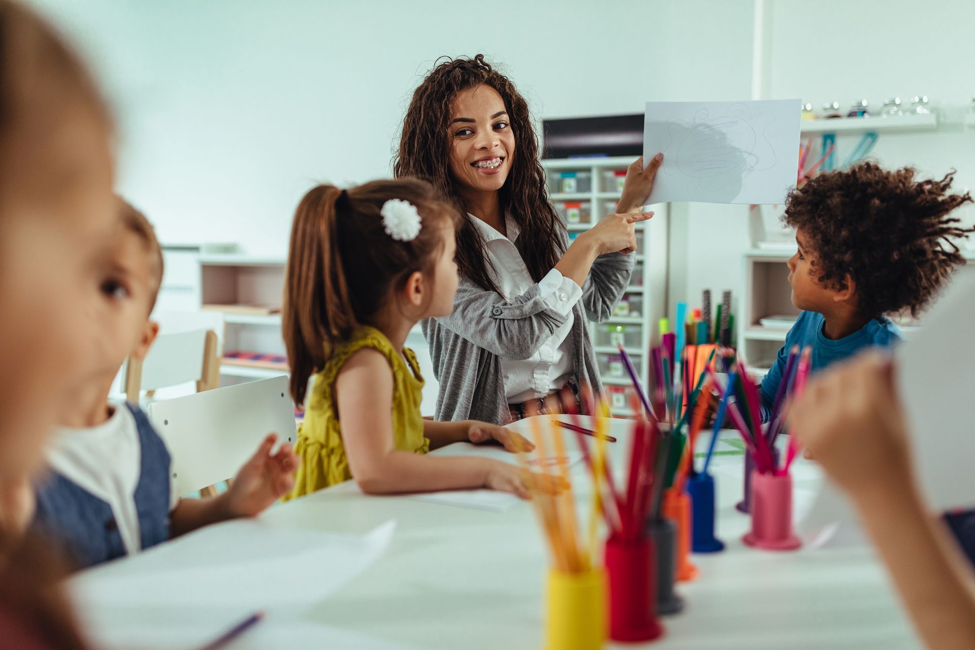 Teacher leading children in a colorful classroom art activity