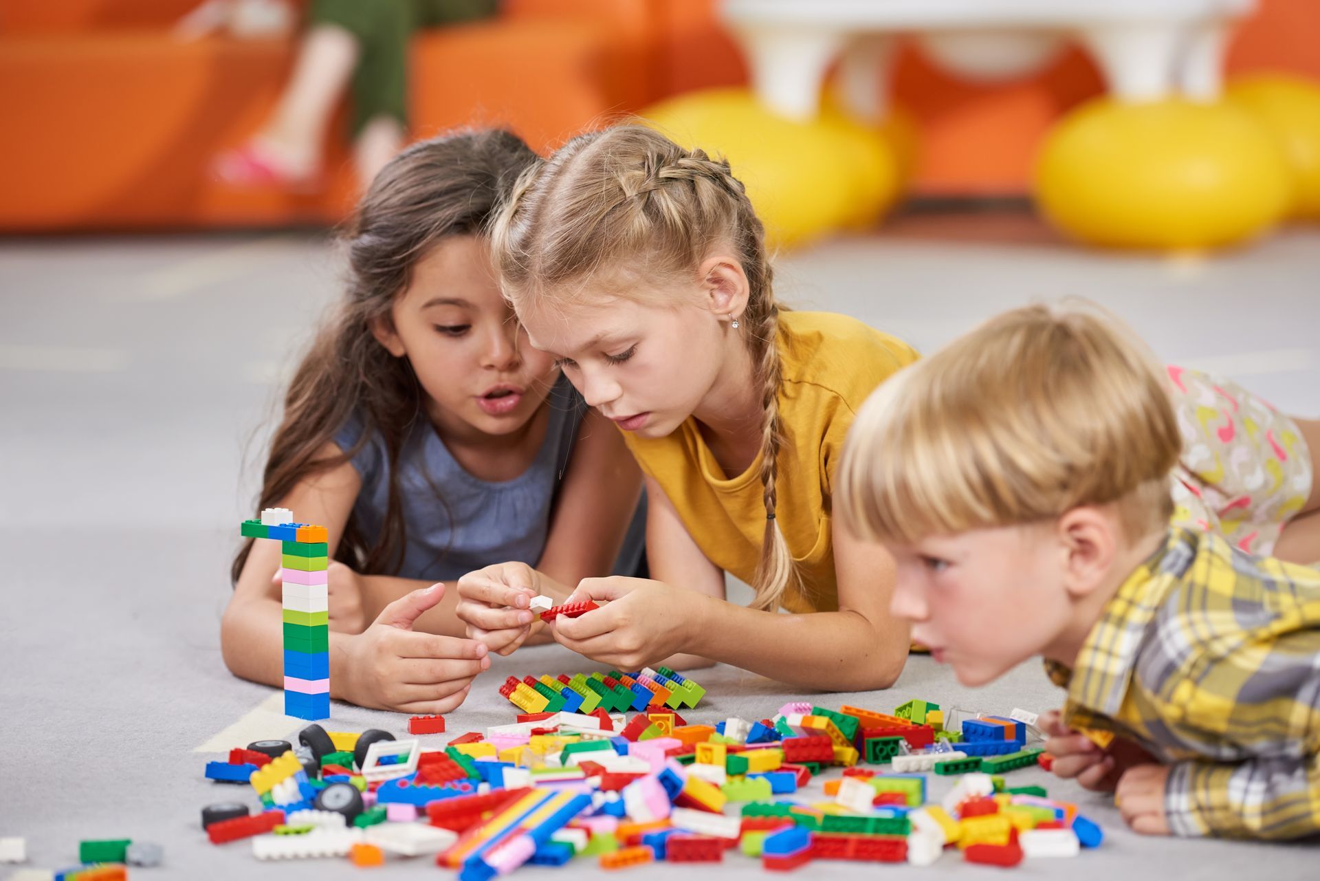 Children playing with colorful building blocks on the floor indoors