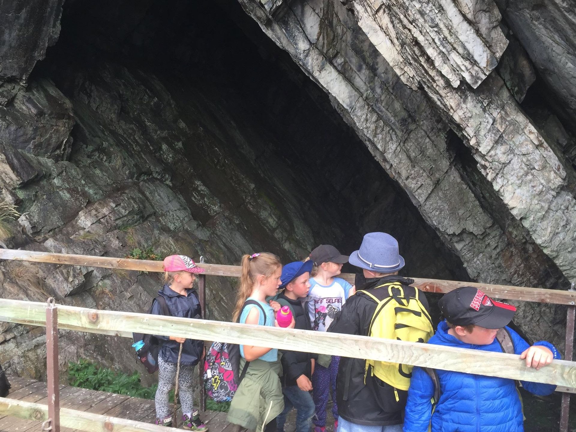 People gathered at a cave entrance, standing behind a wooden railing.