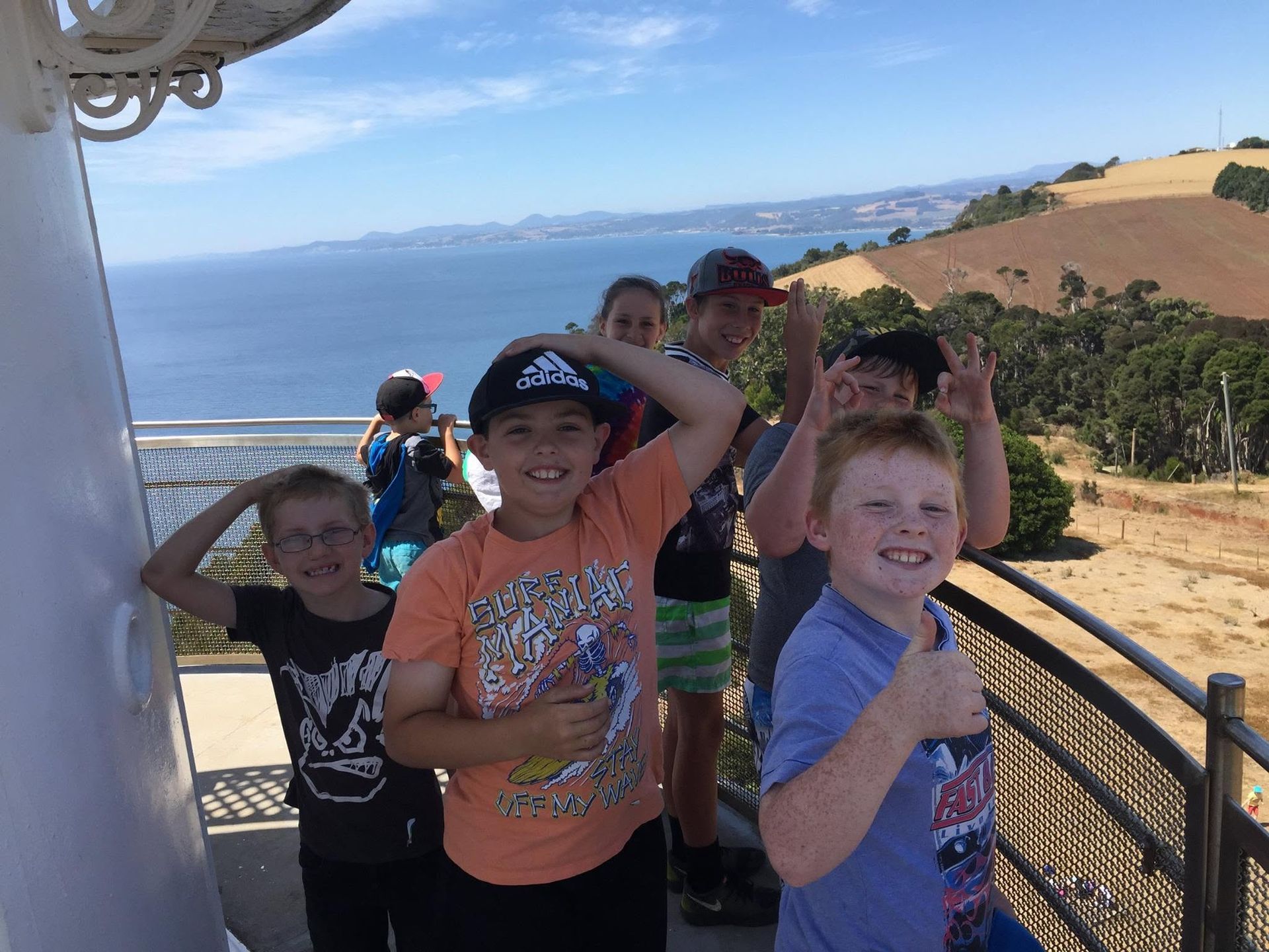 Children posing on a scenic overlook with ocean and hills in the background