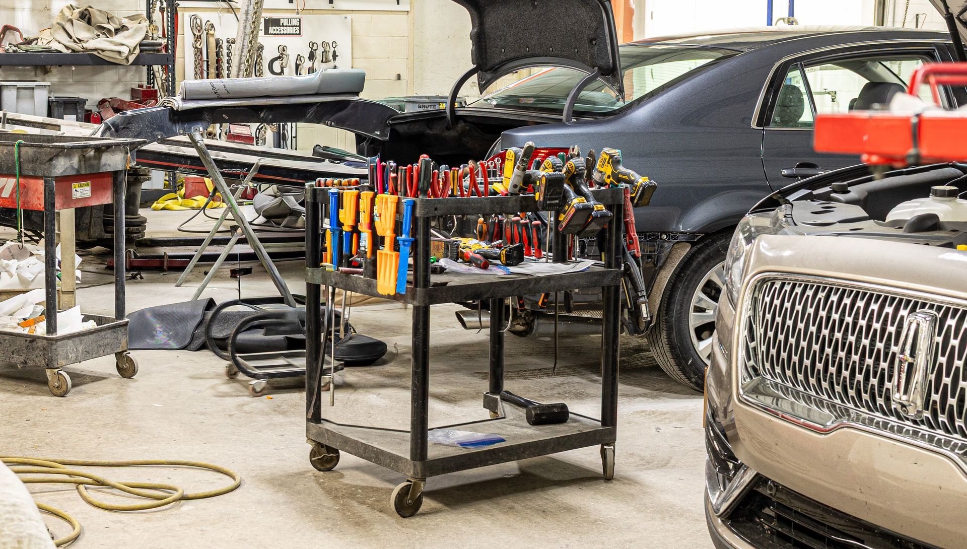 Auto repair shop with a car on the right and a tool cart with clamps in the center