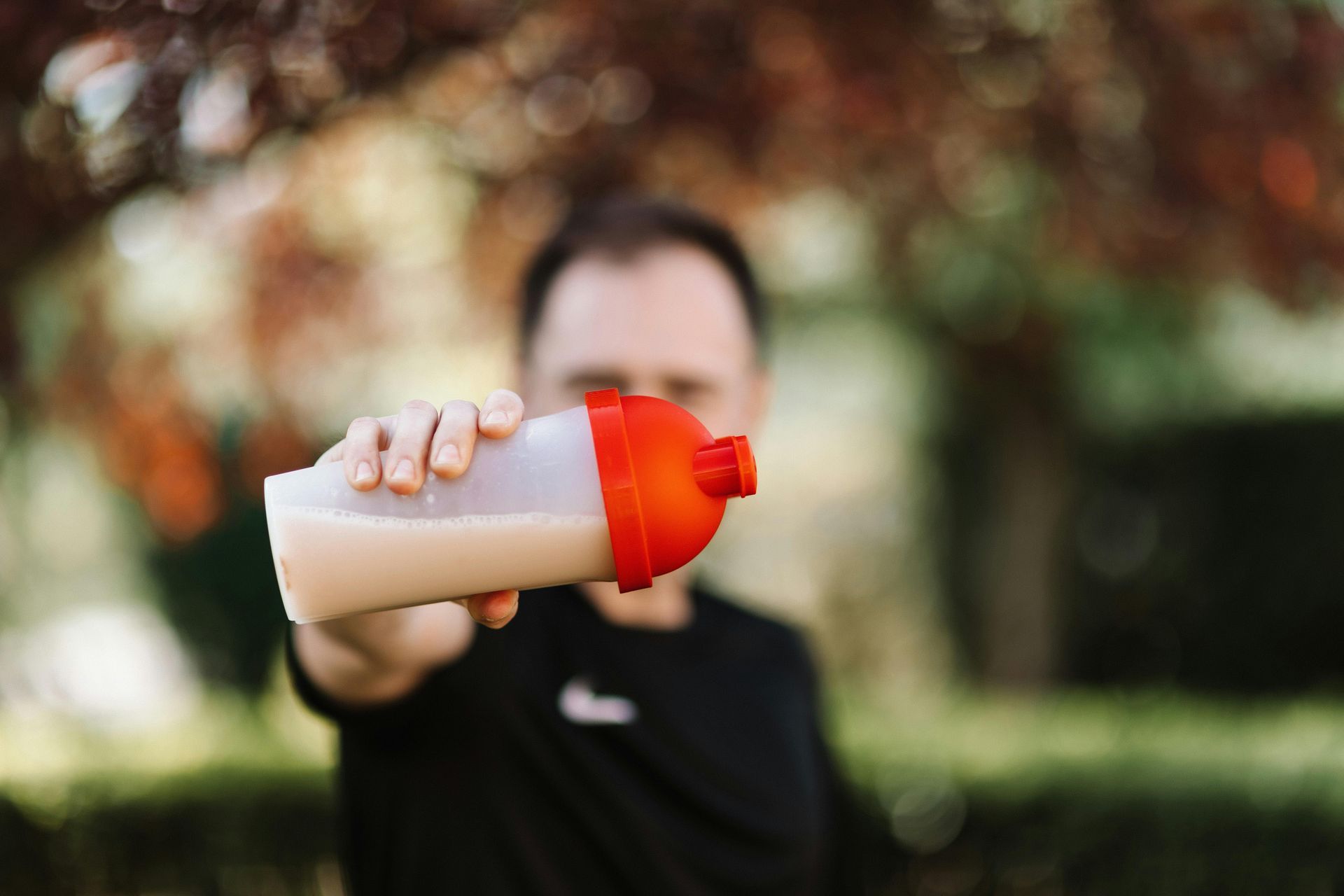 A man is holding a bottle of protein shake in his hand.
