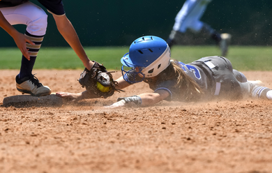 Baseball player sliding into home plate, catcher in front. Blue and gold uniforms, action shot.