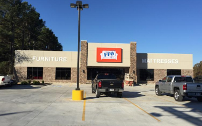 Furniture and mattresses store exterior with parked trucks under a clear blue sky