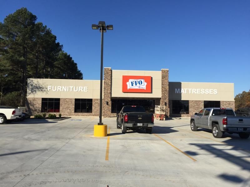 Furniture and mattresses store entrance with parked trucks under a clear blue sky