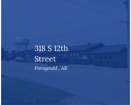 Blue-tinted street view of a building at 318 S 12th Street, Paragould, AR with water tower in background