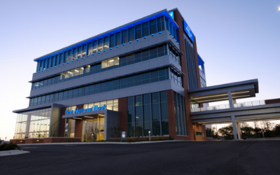 Modern multi-story office building with glass facade and blue accents at dusk