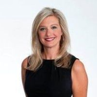 Smiling woman in a sleeveless black top against a light background