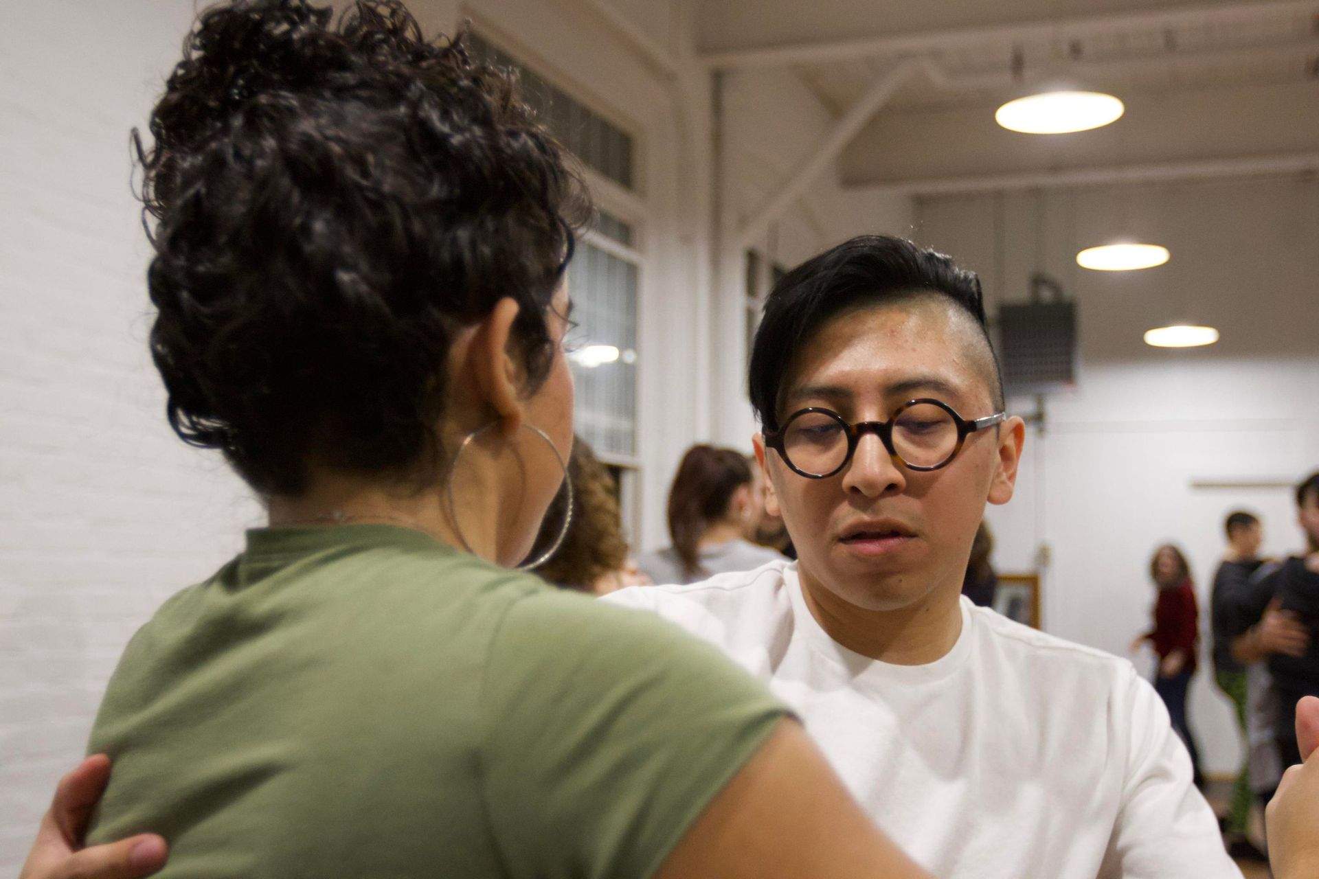 A young man and young woman practice partner work choreography during a Bachata class.