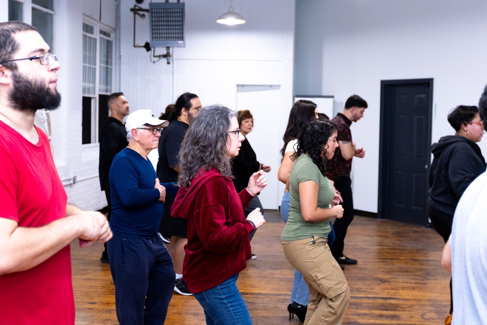 A group of young and older students follow their dance instructors' lead during a salsa class.