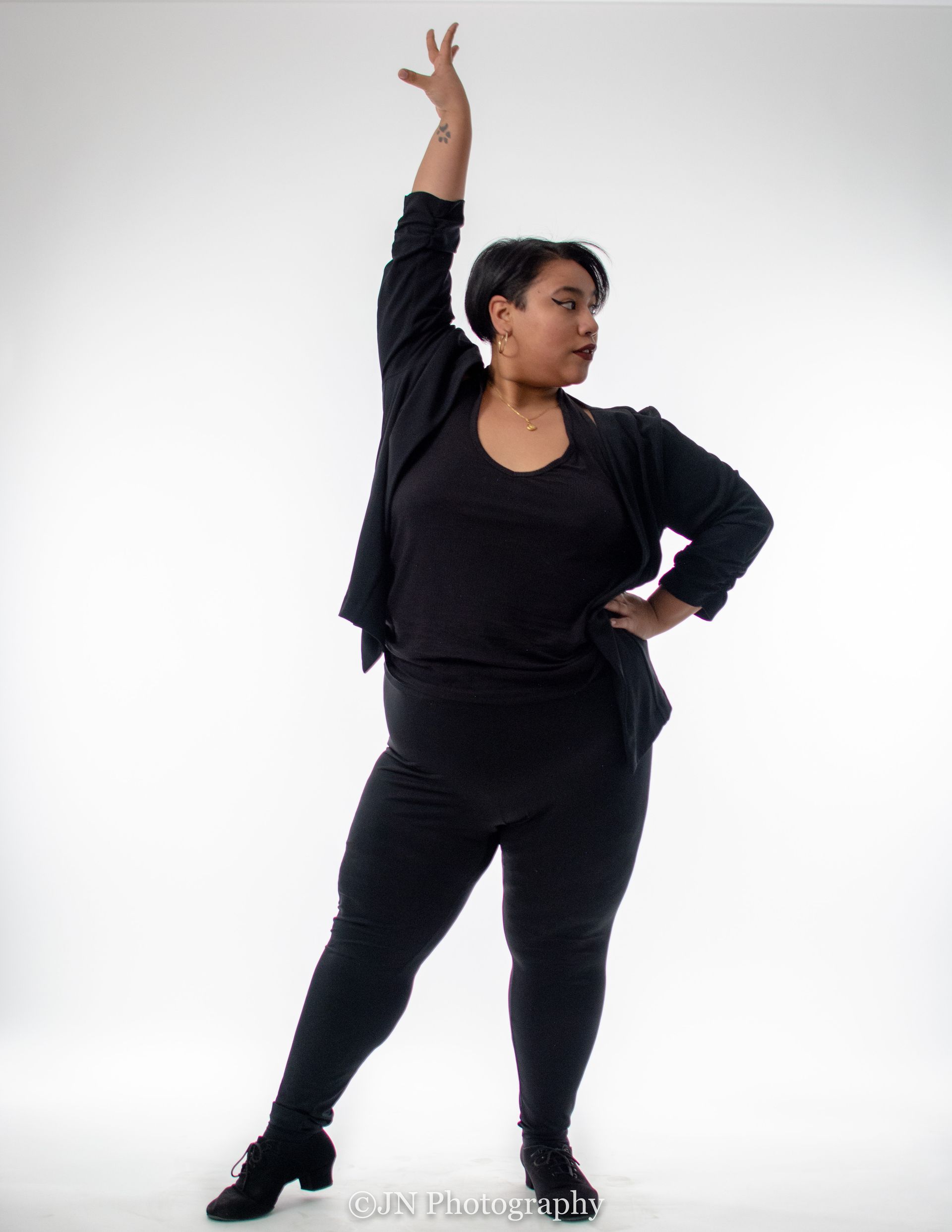 Dance instructor Kristy Berdugo wearing all black and holding a dance pose.