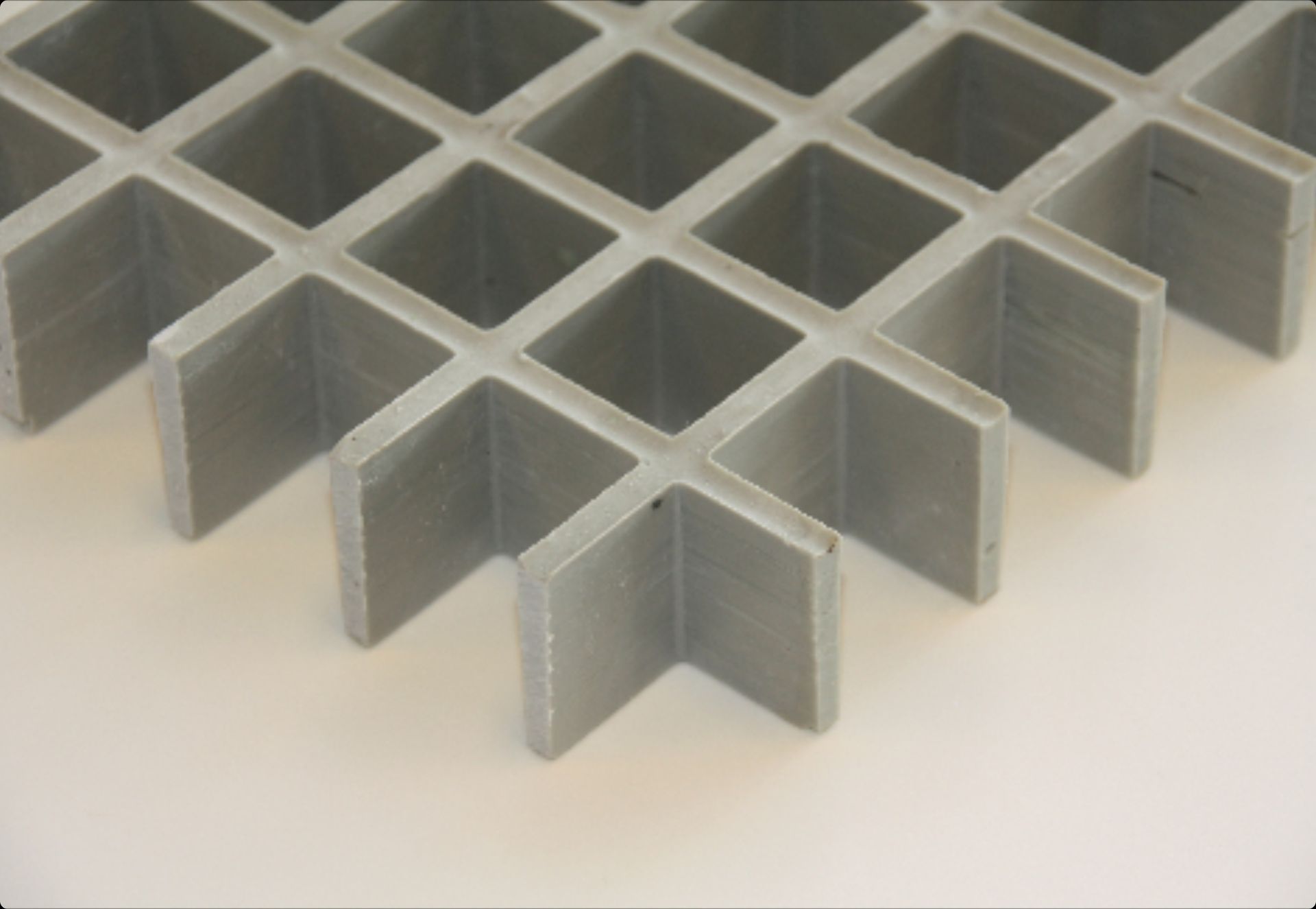 A close-up of a gray, square-grid industrial fiberglass grating panel against a white background.
