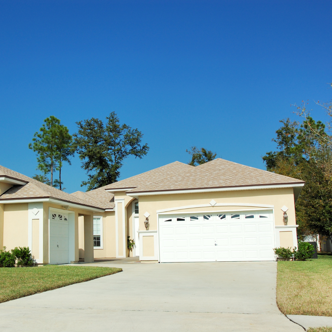 A house with a white garage door and a blue sky in the background