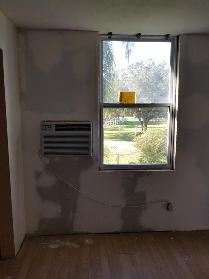 A room with a window and an air conditioner on the wall.