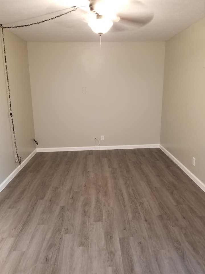 An empty living room with hardwood floors and a ceiling fan.