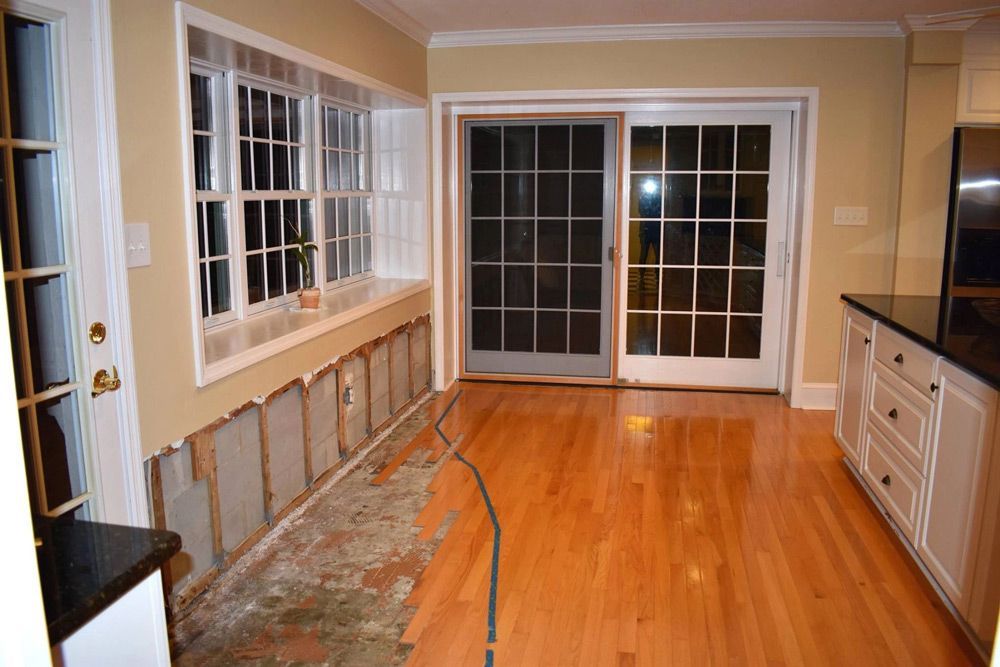 An empty kitchen with hardwood floors and sliding glass doors.