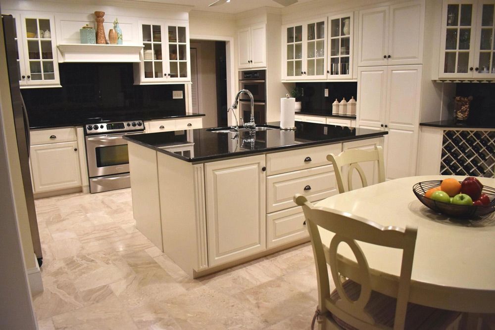 A kitchen with white cabinets and black counter tops