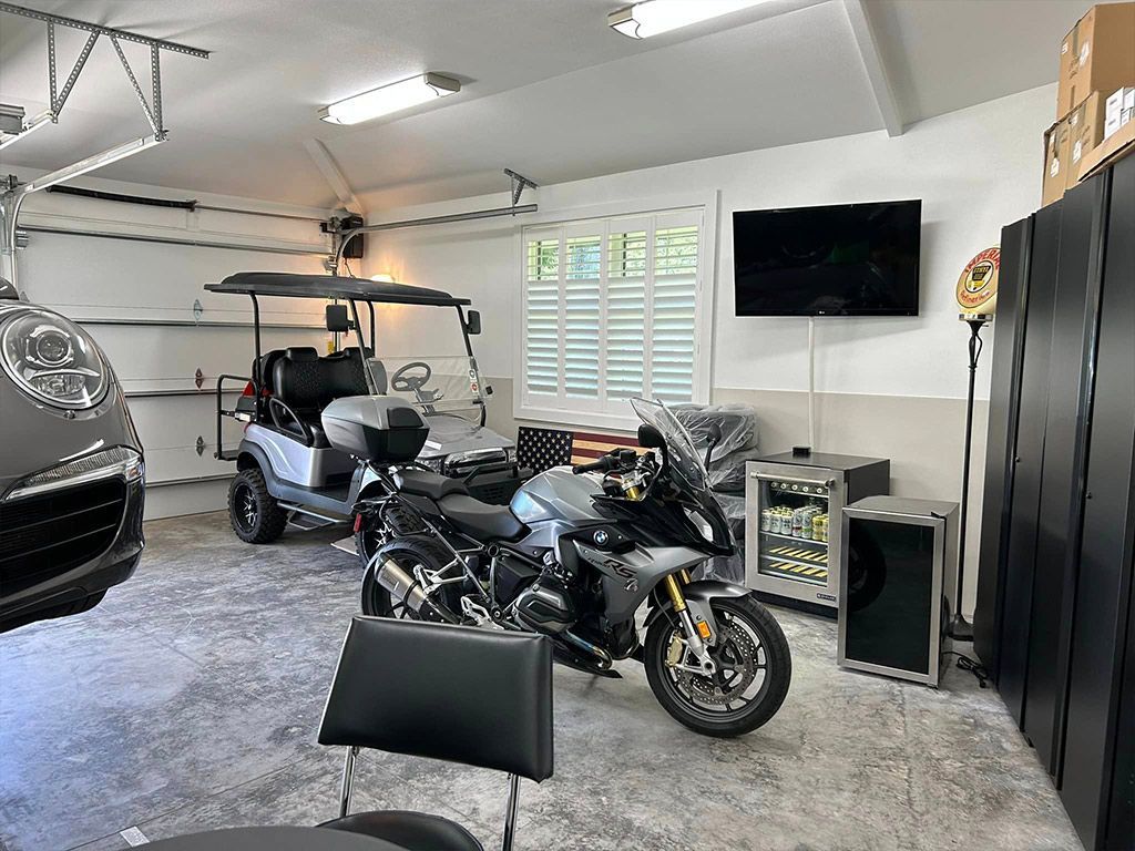 A motorcycle is parked in a garage next to a golf cart.