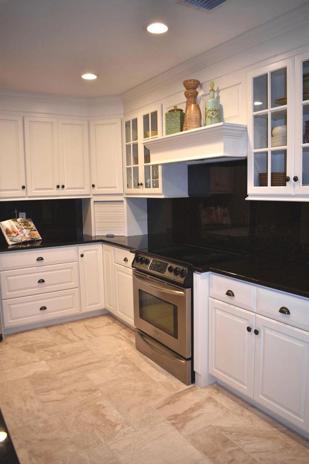 A kitchen with white cabinets and black counter tops
